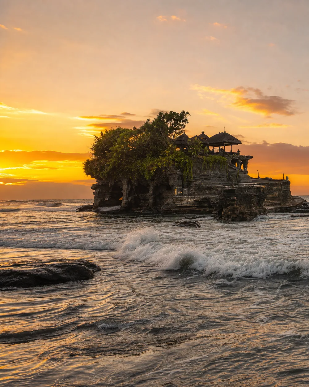 Tanah Lot sea temple silhouetted against a golden sunset sky
